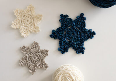 A crochet snowflake in blue, white, and taupe.