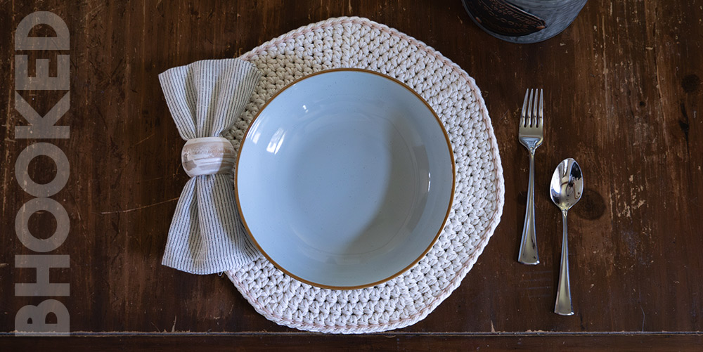 Beige colored crochet placemats on a distressed wooden table